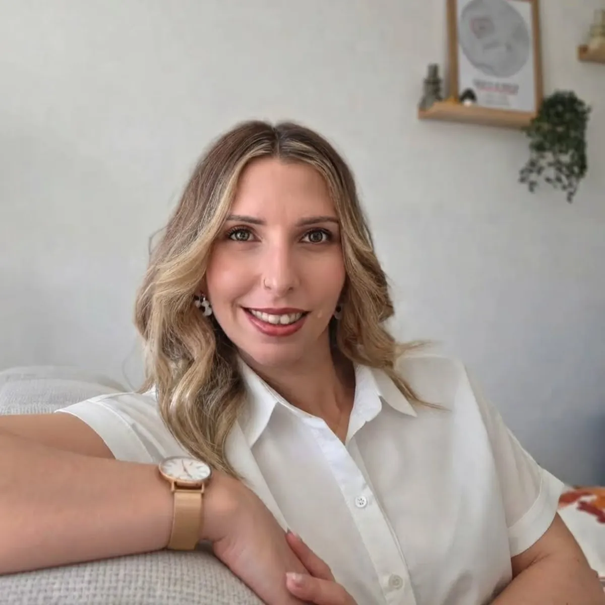 Aude, fondatrice de Célébrations & Co, en chemise blanche, souriante, dans son salon